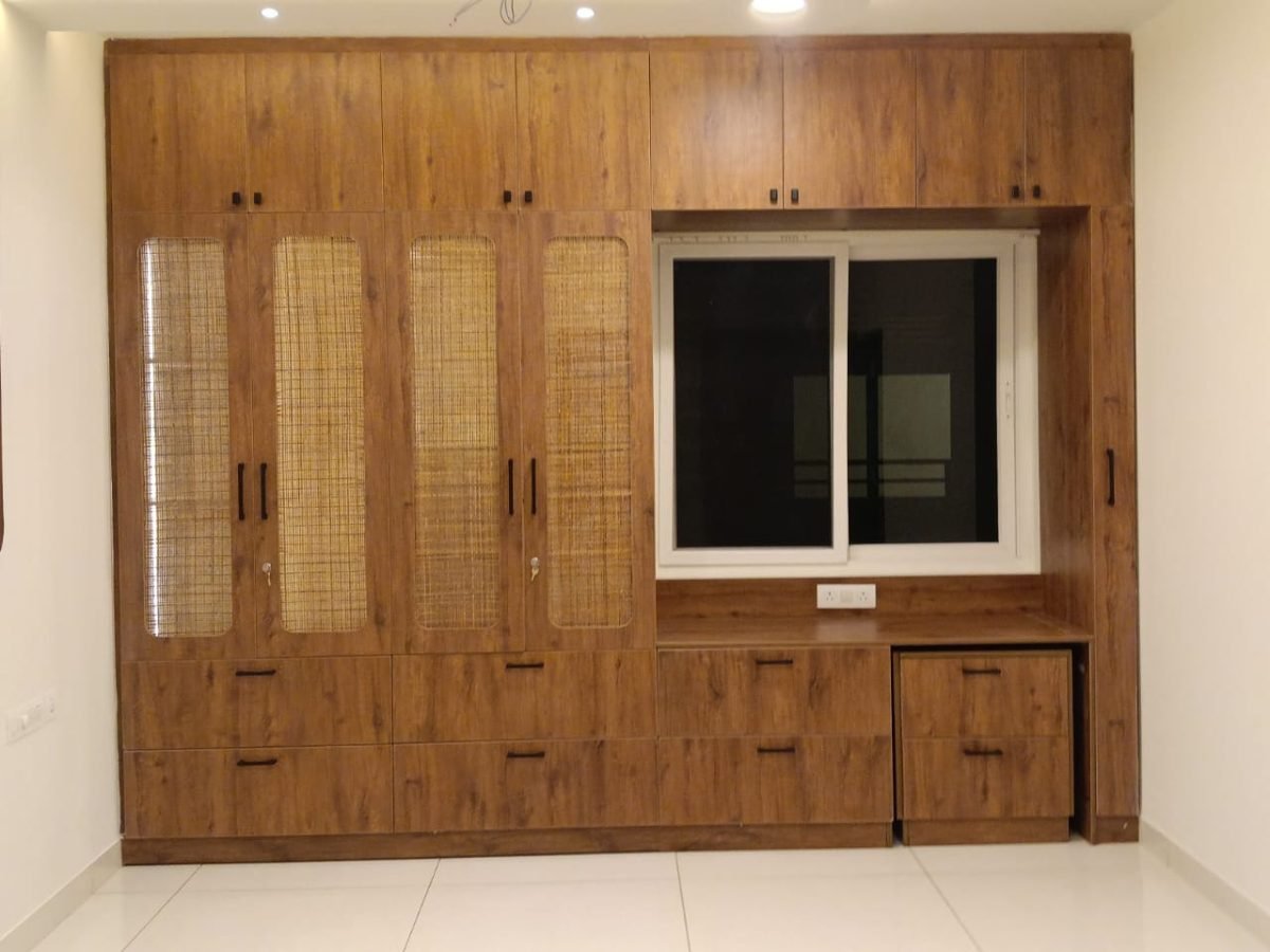 Teak finish wardrobe with cane panel shutters, loft storage, drawer bank and a window side desk